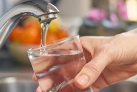 Mano con un vaso bajo el agua de un grifo