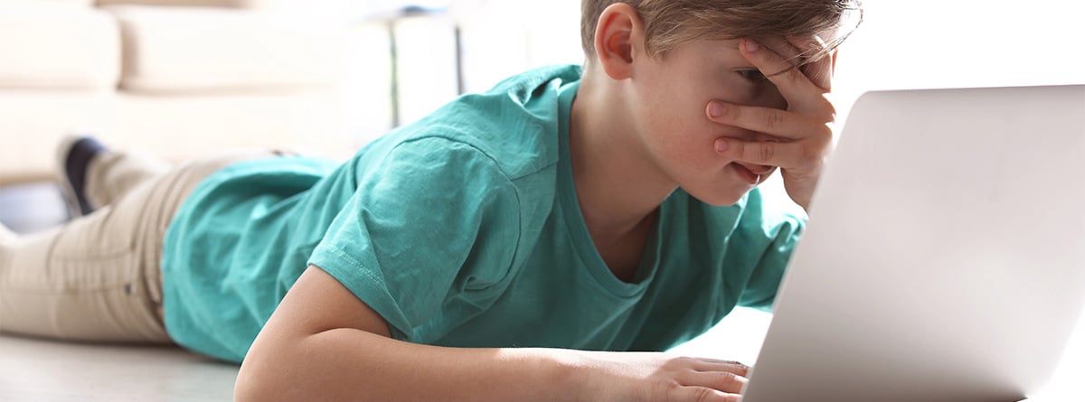 Niño tapándose los ojos mientras mira algo en una tablet