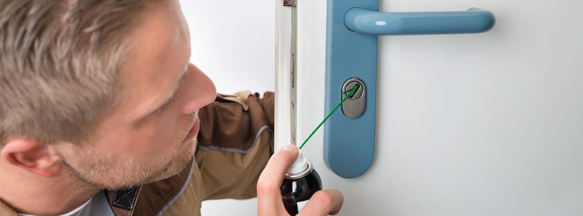 Hombre poniendo lubricante en una cerradura para extraer una llave rota.