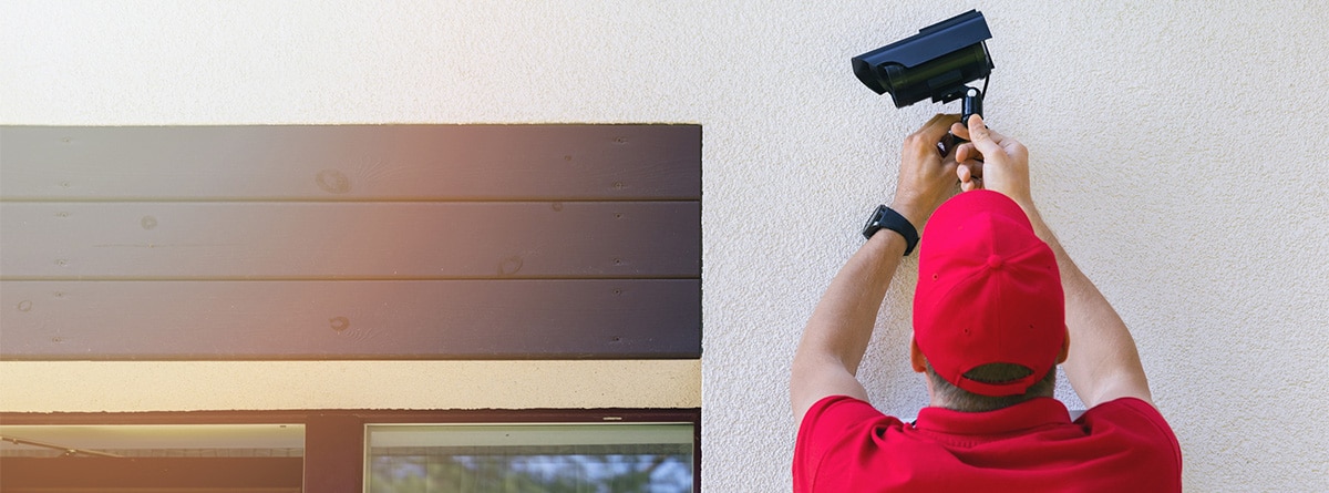 Persona instalando una cámara de videovigilancia en una casa