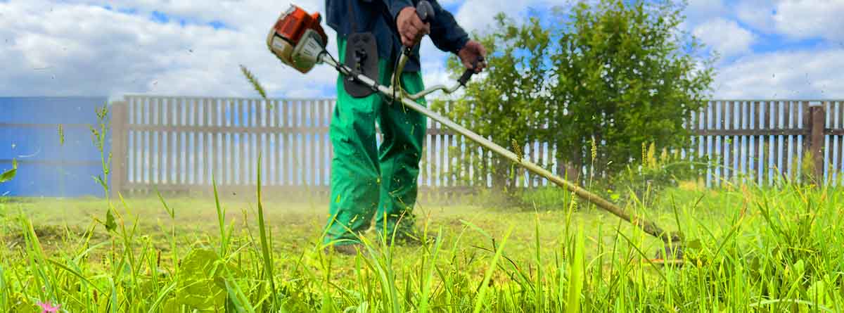 Jardinero pasando una desbrozadora por el cesped