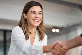 Una mujer sonriente da la mano a otra como firmando un acuerdo