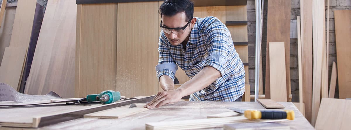 Hombre midiendo con un metro un tablero de madera