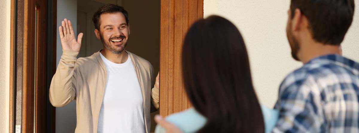 Pareja de vecinos saludando a otro que abre la puerta de su casa