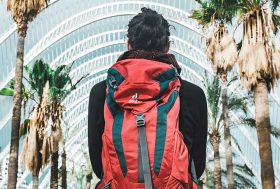 Hombre de espaldas, con una mochila roja puesta