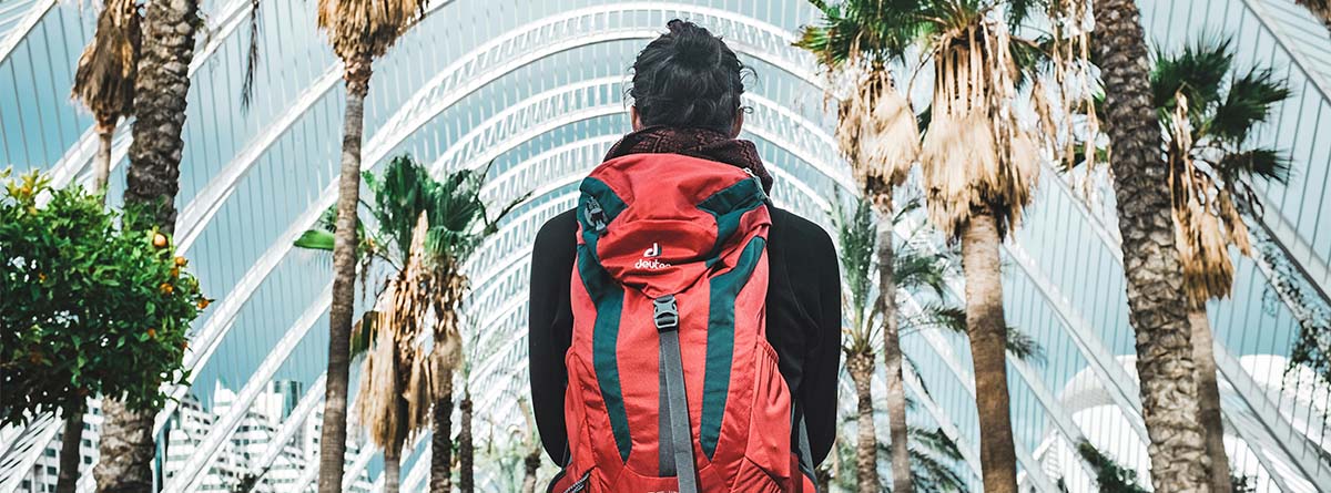 Hombre de espaldas, con una mochila roja puesta