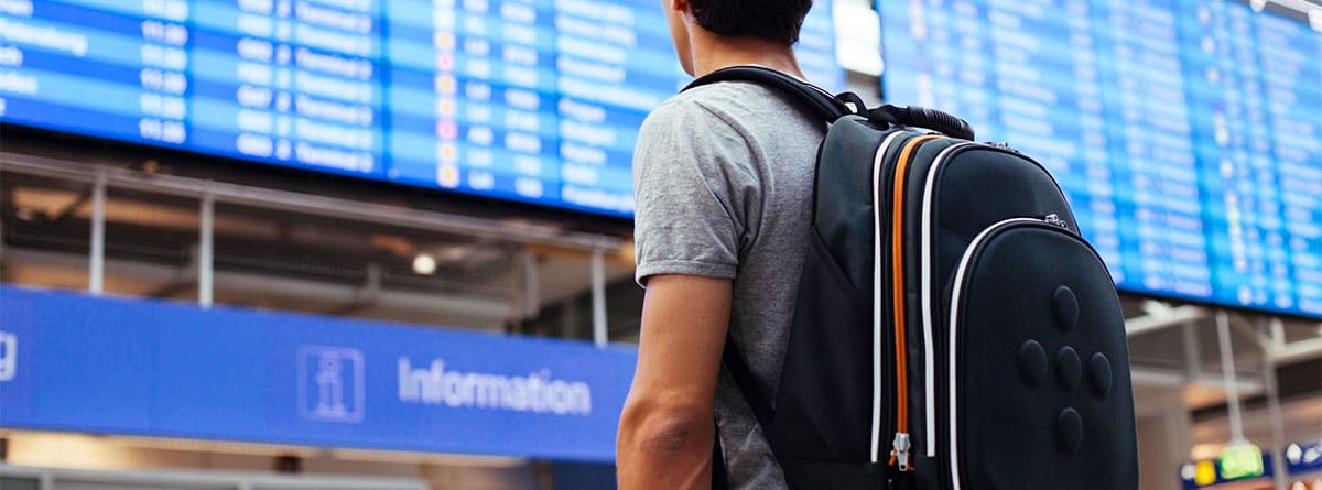 Hombre de espaldas, con una mochila negra puesta, en una estación