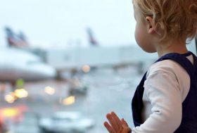 Bebé en un aeropuerto mirando por la ventana de embarque